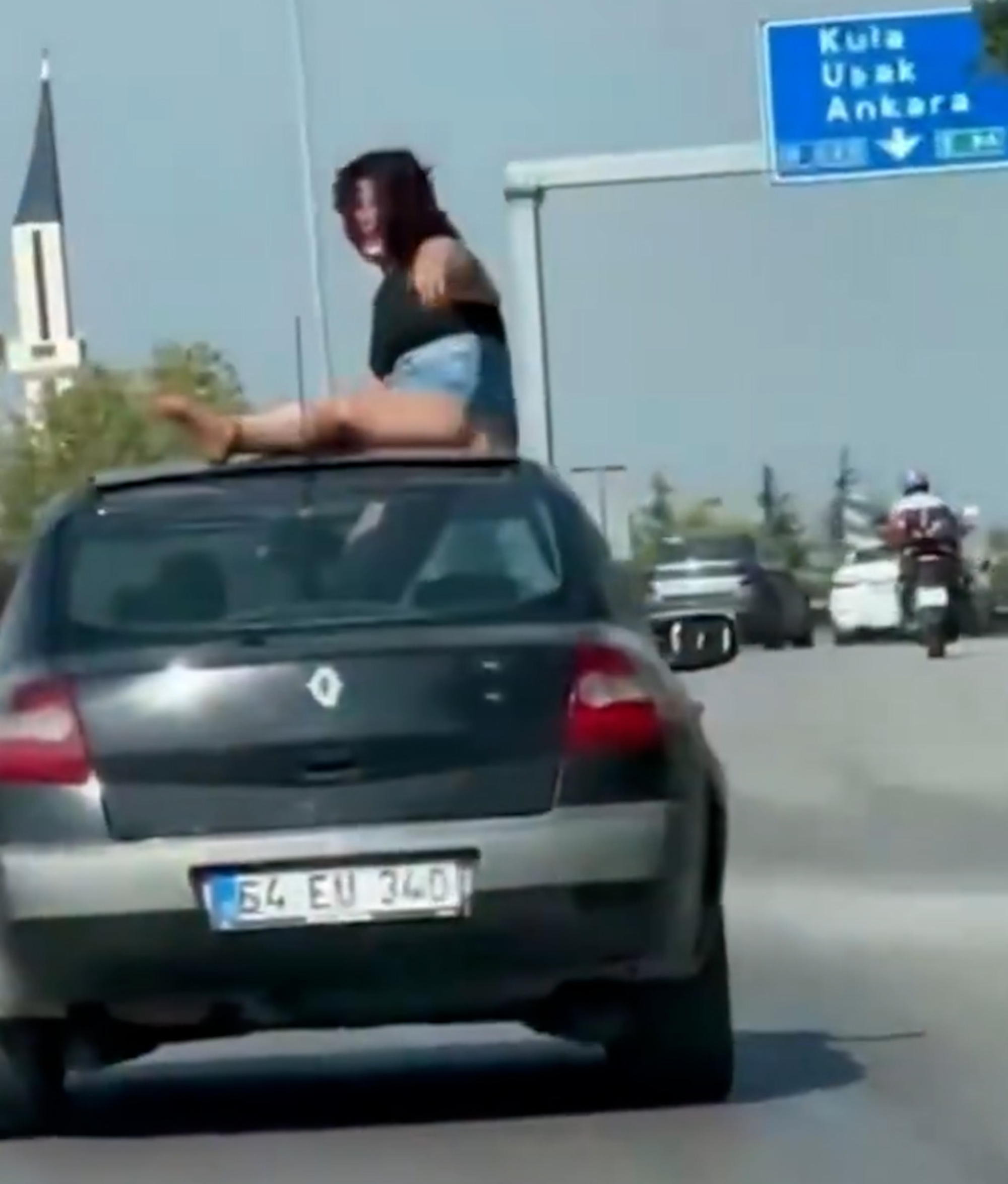 A woman climbs onto the sunroof of a moving car in Manisa, Turkey. The woman and the driver were arrested. Note: Photo is a screenshot from a video. (Newsflash/NX)